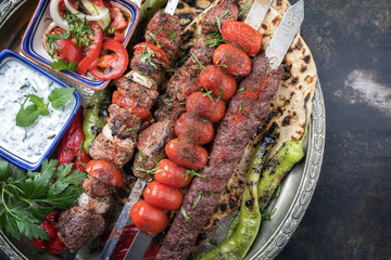 Traditional oriental Adana kebap and shashlik skewer with tomato and flatbread as top view on a...