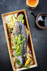 Modern style Japanese bonito tuna fish filet with vegetable and pineapple glazed in teriyaki sauce as top view on a plate