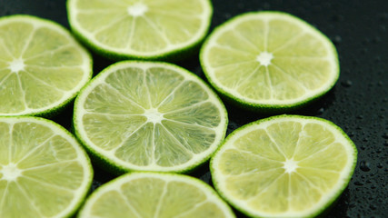 Fototapeta na wymiar Closeup circle slices of fresh sour green lime on dark background 