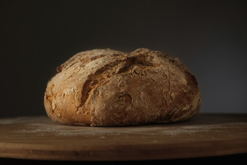 Rye bread of round shape on a wooden backing .