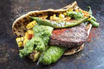 Gardinen Barbecue wagyu hash burger with flatbread, pineapple and chimichurri sauce as top view on an old metal sheet © HLPhoto