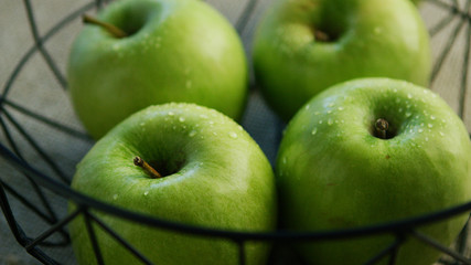 Closeup shot of green healthy apples with water drops on a table 