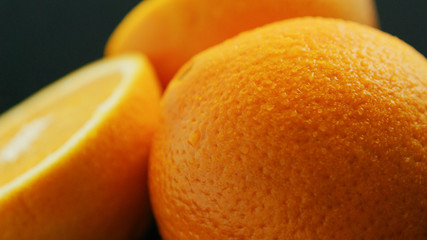 Macro shot of whole and sliced orange on dark background 