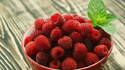 From above closeup shot of fresh ripe raspberry with green leaf in bowl on wooden table  © Dash