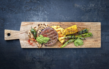 Barbecue wagyu hash burger with flatbread, pineapple and chimichurri sauce as top view on a cutting...