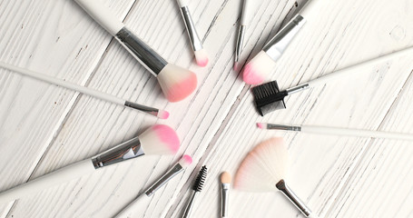 From above view of makeup brushes of different kind laid in circle on wooden background