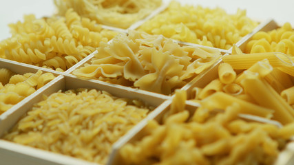 From above view of box with sections full of macaroni of different type on white background