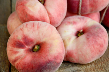 Saturn peach or Dough nut peaches on wooden background and sack cloth.