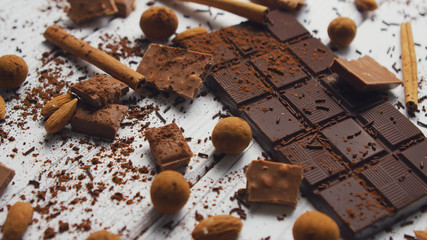 Closeup of arranged mess of black chocolate bar with milk chocolate pieces and spices on wooden...