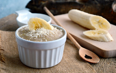 Thailand traditional dessert .
Steamed Banana Cake (Thai name is Kanom Gluay) with white cup on wooden background.