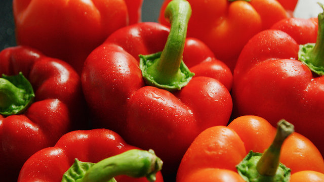 Closeup from above view of ripe red peppers with green stems in heap