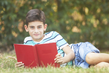 Fototapeta premium Young boy reading at the park