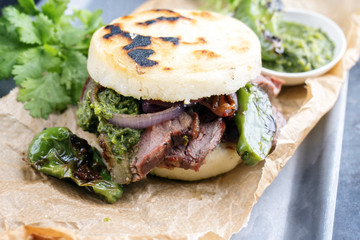 Traditional Columbian arepa con carne desmechada with shredded beef steak and aji criollo as closeup on a backing paper