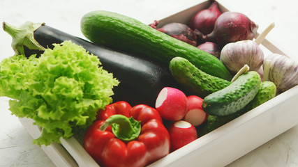 From above of box filled with various fresh vegetables in daylight 