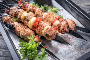 Traditional Greek souvlaki barbecue skewer with tomato, onion and paprika as closeup on a metal griddle