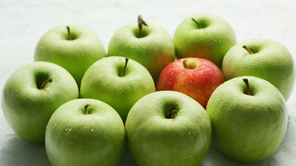 Composition of ripe and juicy green apples with one red in middle on table in daylight
