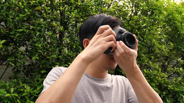 Orbit circle shot of young male photographer taking photos in nature scenery