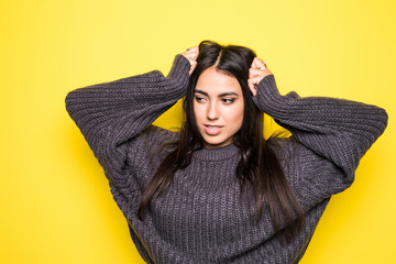 Beautiful young woman sweater smiling, and looking at camera on yellow background.