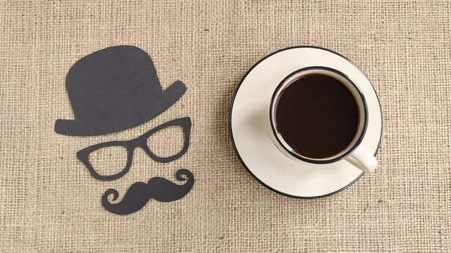 Male silhouette pattern with mustache, glasses and hat with cup of coffee on the burlap background. Movember concept. Prostate Cancer and men's health awareness
