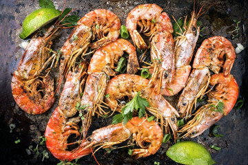 Traditional fried black tiger prawn with lemon as top view on a rustic old board