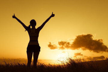 Feeling positive. Happy female out doors at sunset  with thumbs up.
