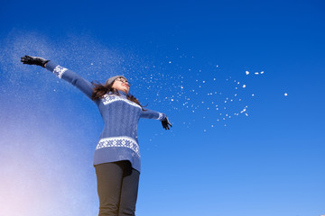 Fototapeta na wymiar girl in a warm sweater throws snow and bask in the winter sun