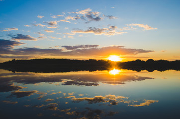 Quiet surface of the river on the background of a colorful sunset.Beautiful landscape of nature.