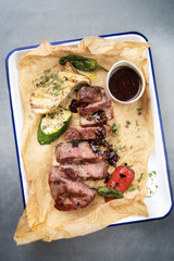 Traditional German barbecue sliced rostbraten with fried mushrooms and paprika as top view on backing paper in a skillet