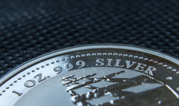 A part of a pure silver ounce coin on black structured background. 