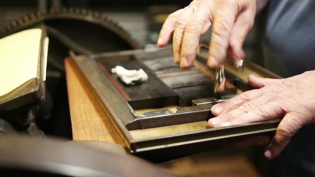 Letterpress printer tightens printing chase, and wipes metal type 