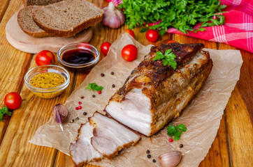 Roast pork belly in mustard honey glaze on a dark wooden background. Rustic style.