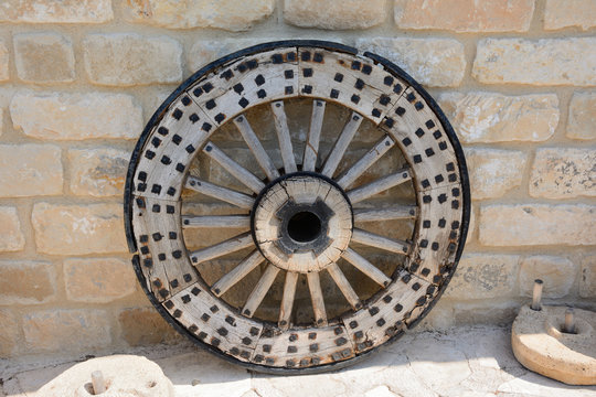 old, ancient wooden wheel with a metal rim, against the background of a stone wall