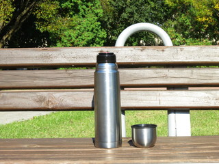 Thermos and Cup on the outdoor bench in the Park