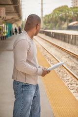 Fototapeta premium The African American black man holding paper looks back to see if a train is coming.