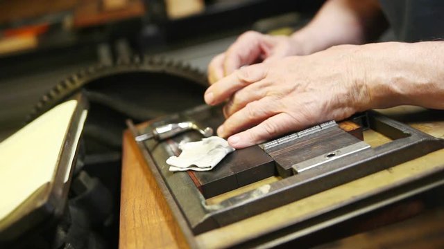 Senior man uses a magnifier to check metal type placement