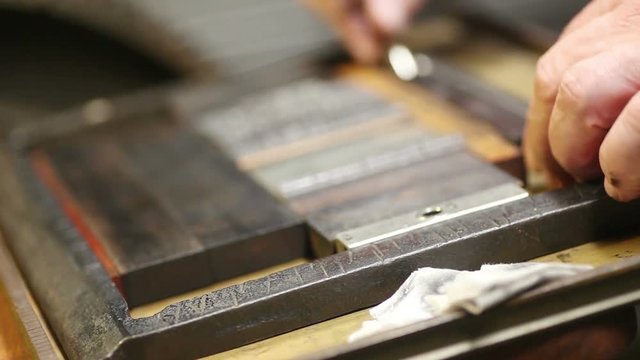 Letterpress printer uses a quoin key to secure a block of metal type in a chase