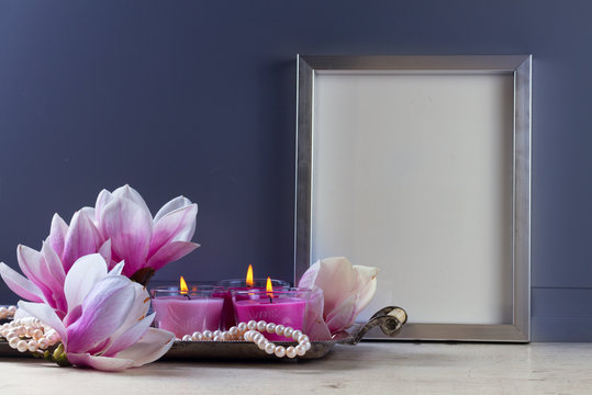 Gray room interior decor with fresh magnolia flowers, burning hand-made candle and poster mock up