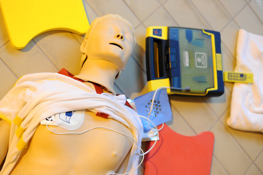 CPR training using and an AED and bag mask valve on an adult training manikin. First aid cardiopulmonary resuscitation course using automated external defibrillator device, AED.