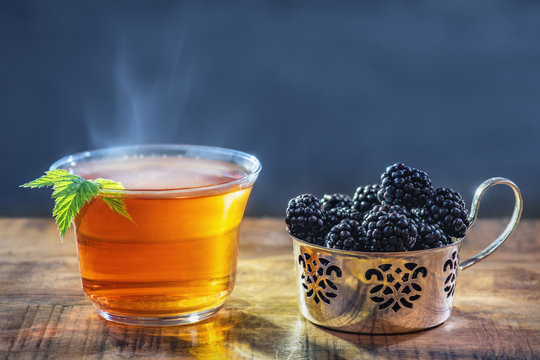 Tee hei&szlig; in Teetasse mit Dampf und Brombeere frisch