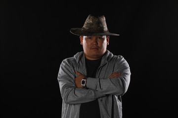 studio portrait of an Asian guy in a hat on a black background