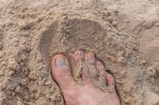 Męska stopa w piachu na plaży