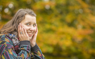 Close up Portrait of beautiful young smile woman in fall beech forest with yellow leaves around. Detail view on girl beauty with empty space in easy colorful background of tree crown.