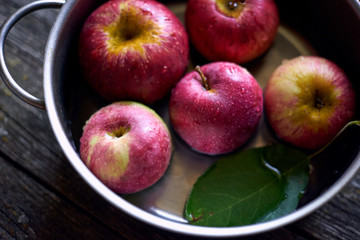 fresh ripe apples in an iron pan on a wooden table top view