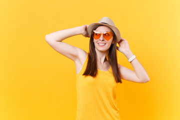 Portrait of excited smiling young woman in straw summer hat, orange glasses put hands on head, copy space isolated on yellow background. People sincere emotions, lifestyle concept. Advertising area.