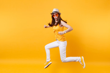Fototapeta na wymiar Portrait of excited smiling young jumping high woman in straw summer hat, orange glasses copy space isolated on yellow background. People sincere emotions, passion lifestyle concept. Advertising area.