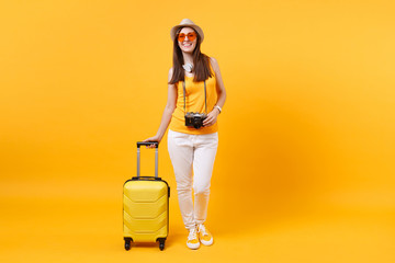 Traveler tourist woman in summer casual clothes, hat with headphones on neck isolated on yellow orange background. Passenger traveling abroad to travel on weekends getaway. Air flight journey concept.