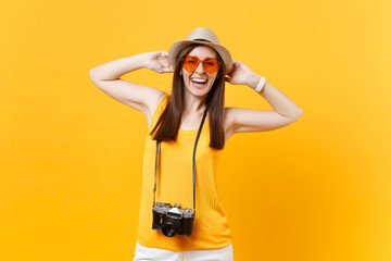Fototapeta na wymiar Happy traveler tourist woman in summer casual clothes, hat with retro vintage photo camera isolated on yellow orange background. Girl traveling abroad travel on weekends getaway. Air flight concept.
