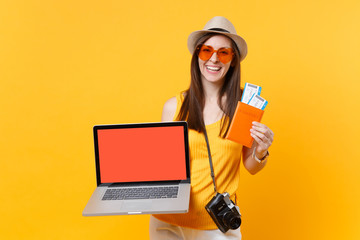 Tourist woman holding laptop pc computer with blank black empty screen passport tickets isolated on...
