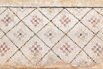 Ancient, antique mosaic of small colored tiles with geometric pattern.