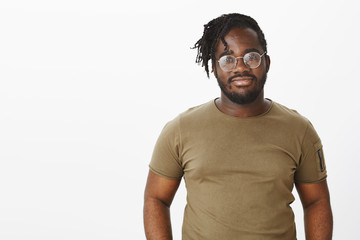 Indoor shot of beautiful african american in casual t-shirt and glasses, smiling and staring at...